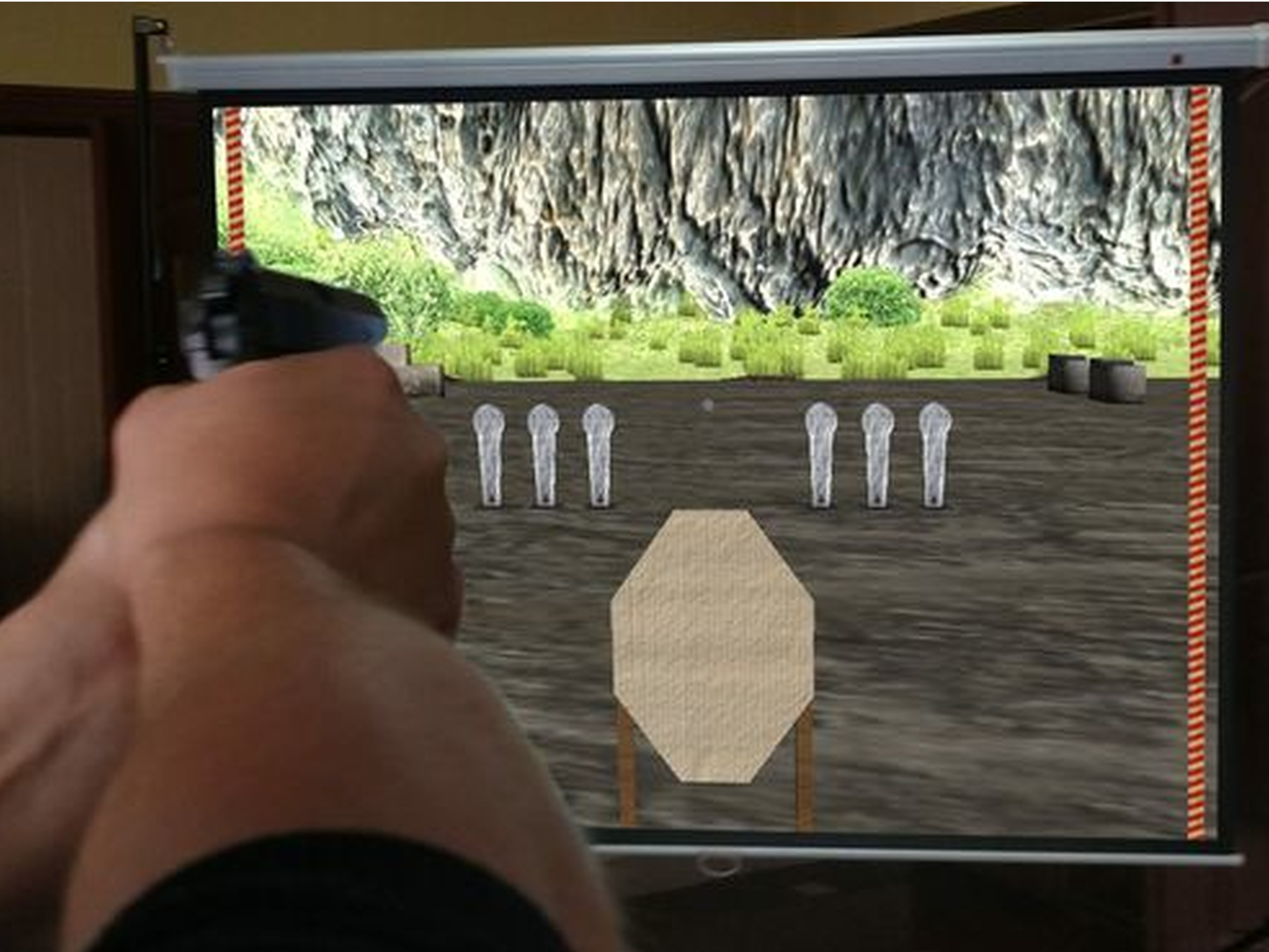 Спортсмен-любитель тренеруется дома стрельбе из пистолета по мишеням IPSC, отображенным на экране лазерного тира